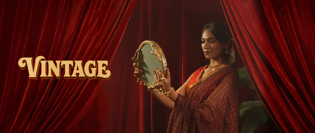 Woman in black and gold vintage saree against a red curtain backdrop