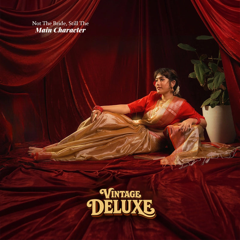 Woman reclining in a gold and red vintage deluxe main character saree against red curtains, Kottanz Loom Co
